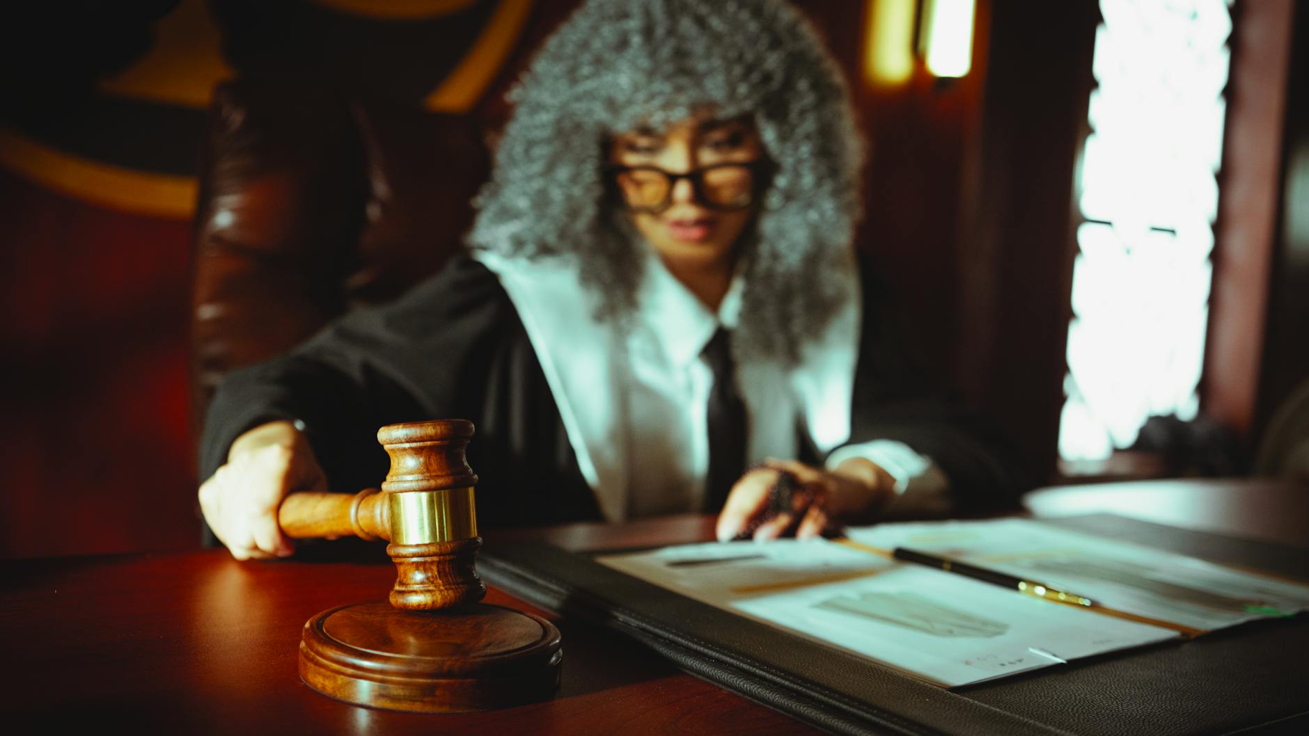 Female judge in a courtroom setting, focusing on legal documents with a gavel.