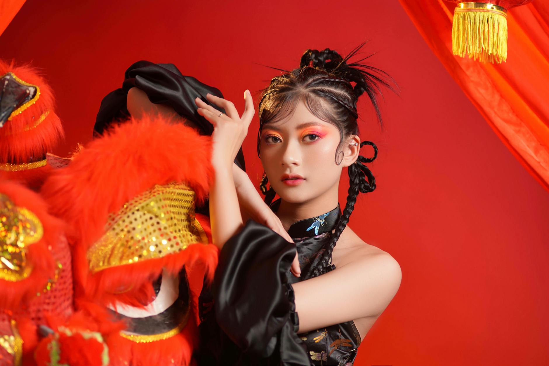 Stylish Asian woman poses with Chinese lion head against vivid red background.