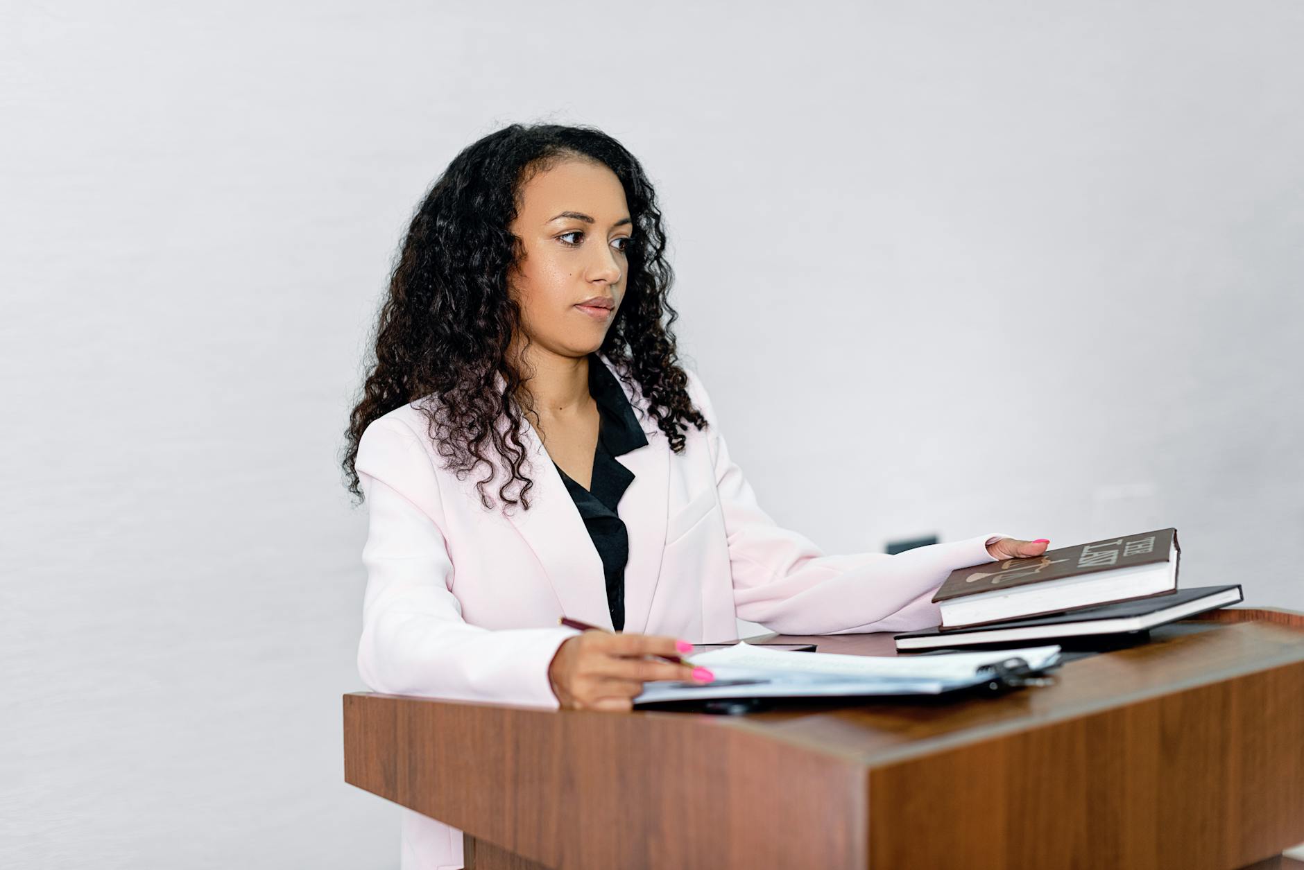 A professional black woman lawyer presenting documents at a podium with books.