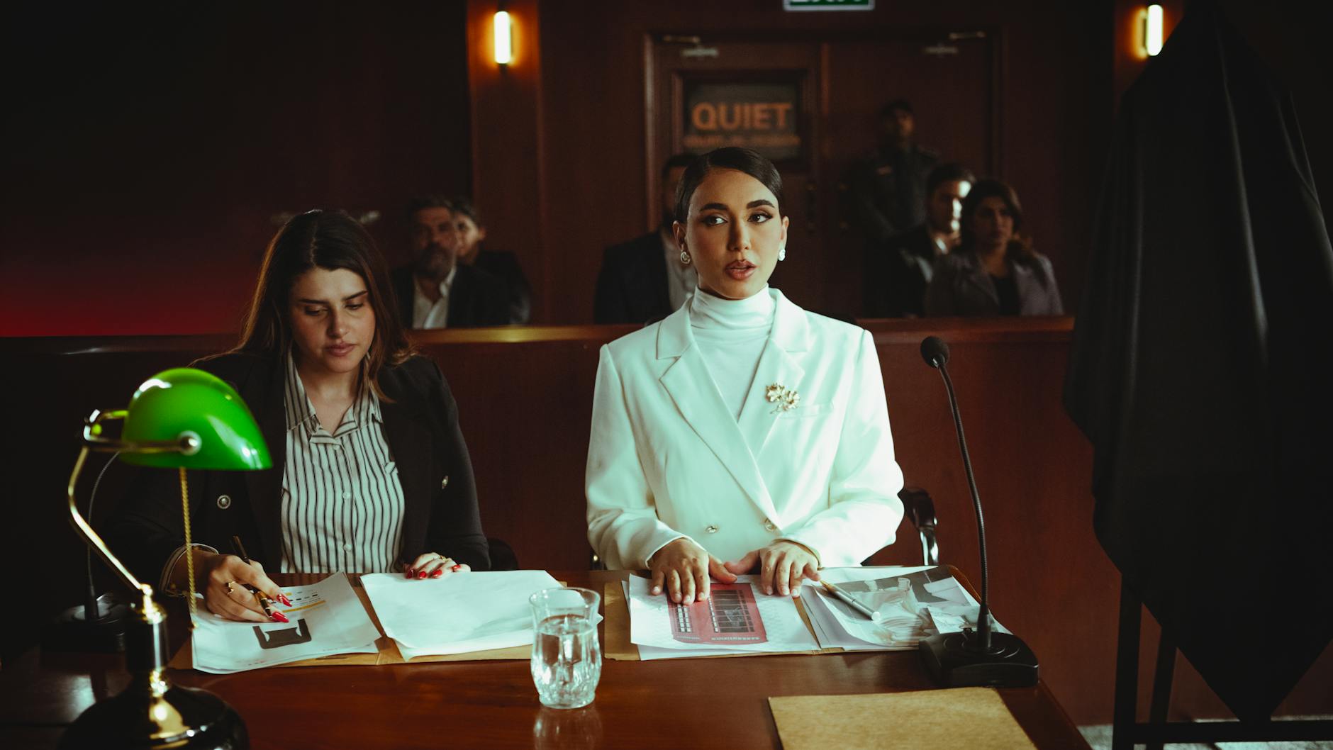 Two female lawyers in a courtroom setting, focusing on legal documents and poised presentation.