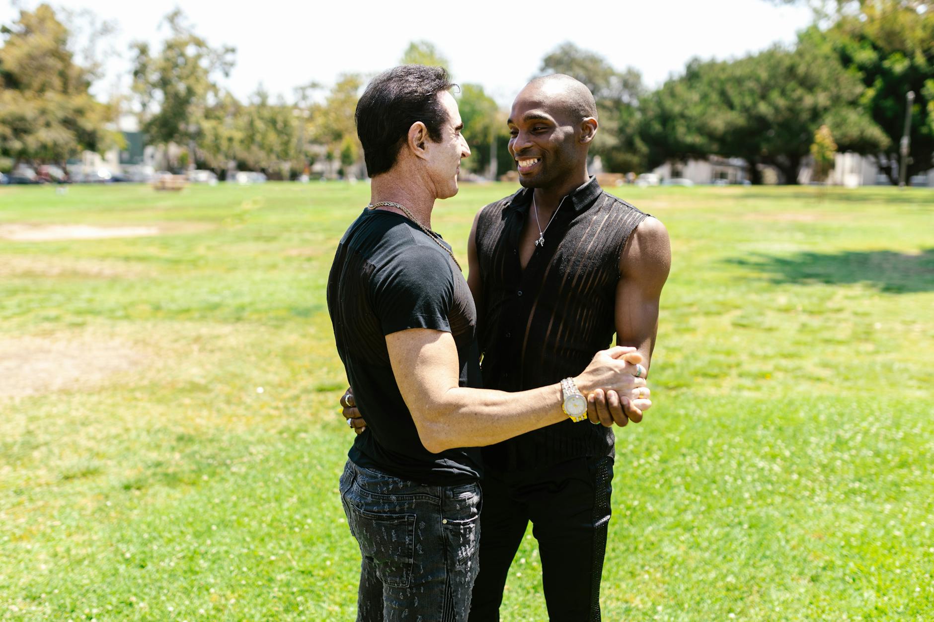 Joyful couple dancing together outdoors in a sunlit park.